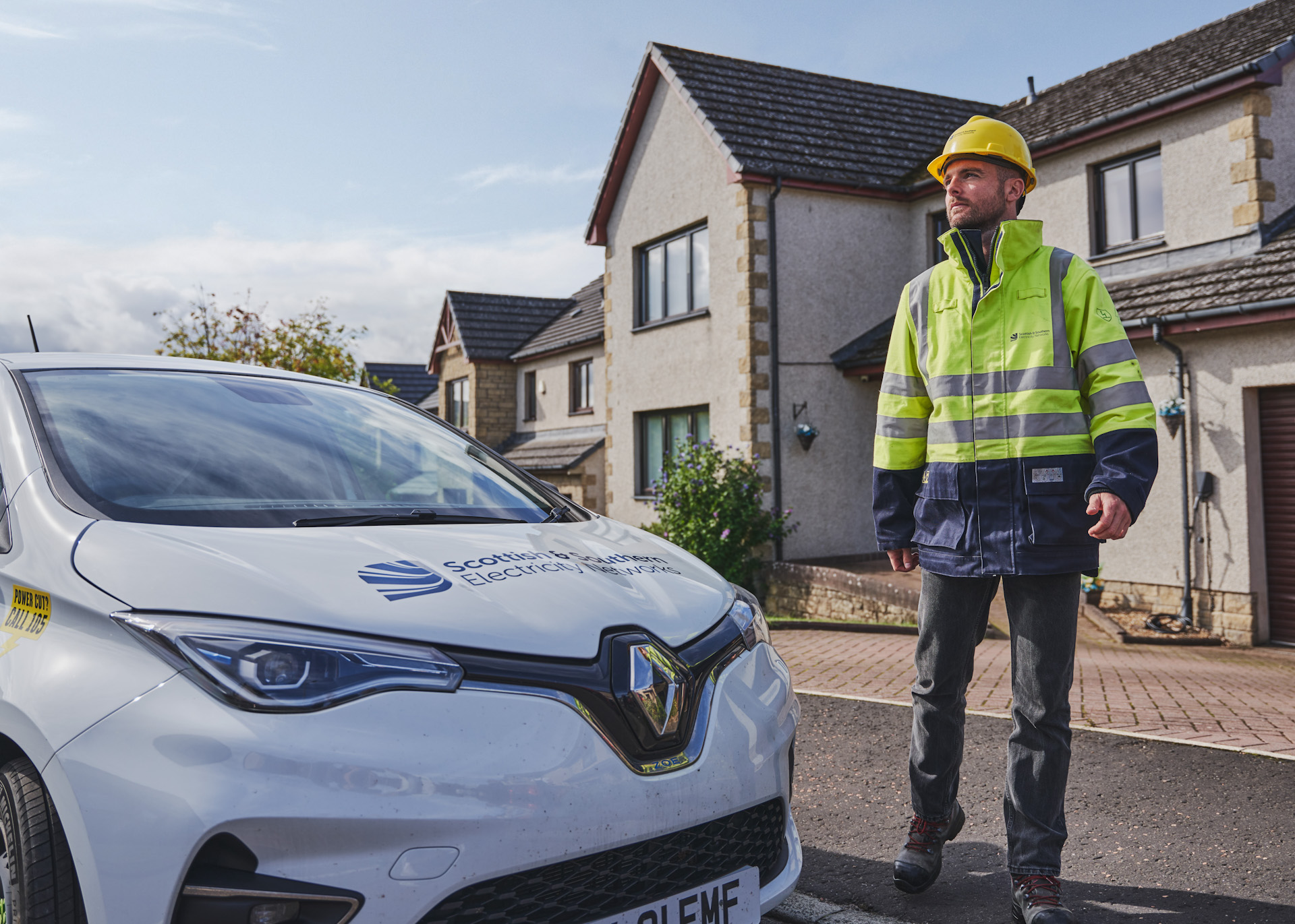 Engineer standing at EV car outside of house