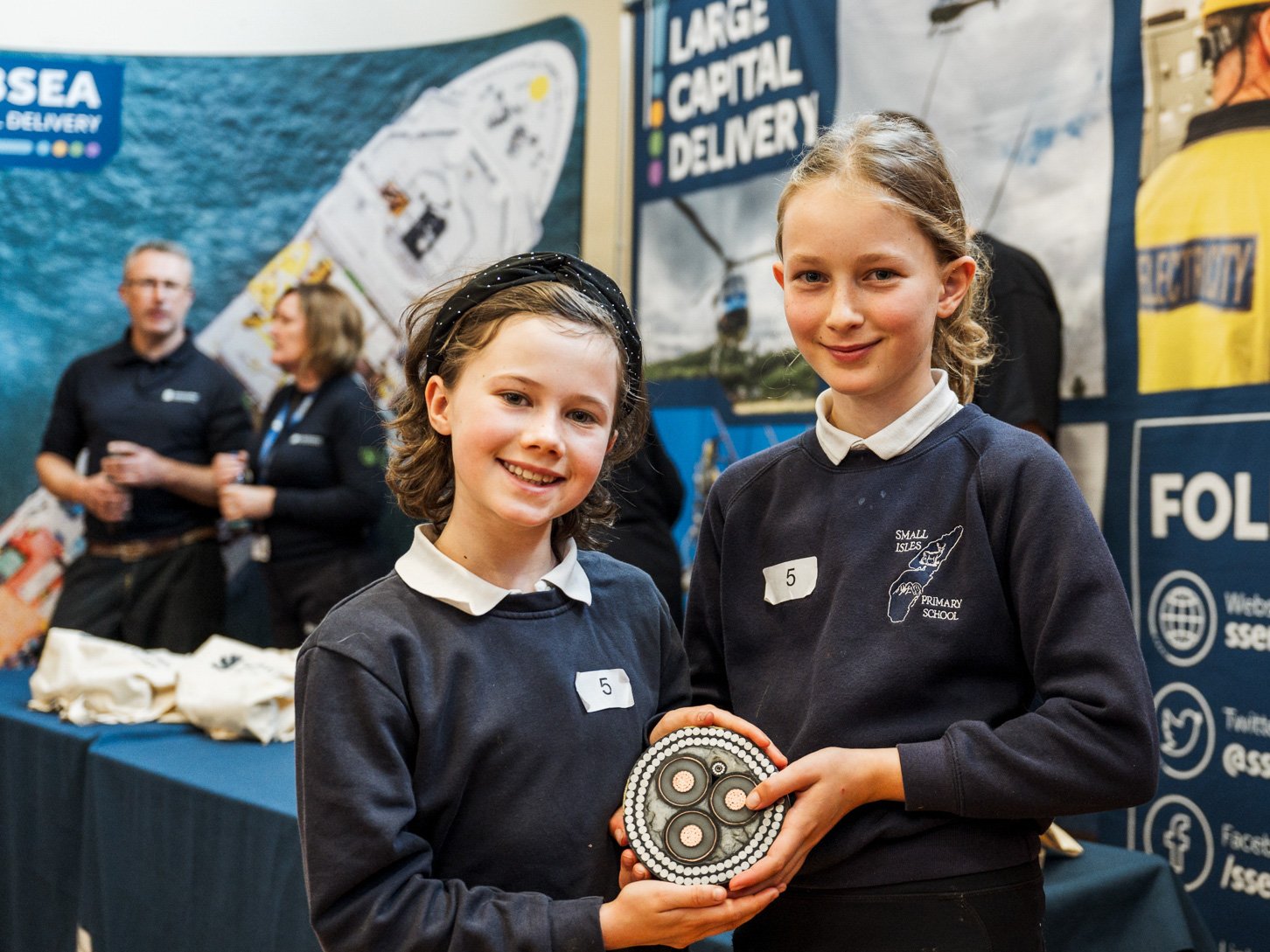 Two school pupils holding a cross-section of a subsea cable