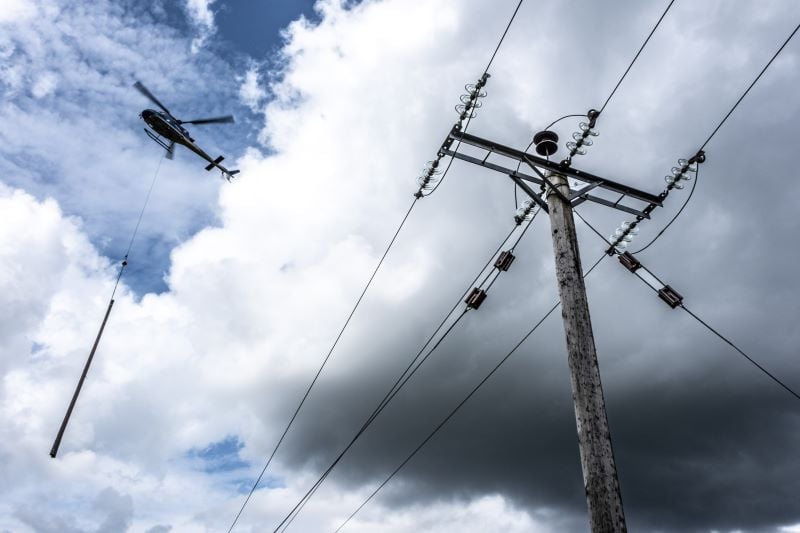 A picture of SSEN's network being upgraded with a helicopter delivering replacement poles