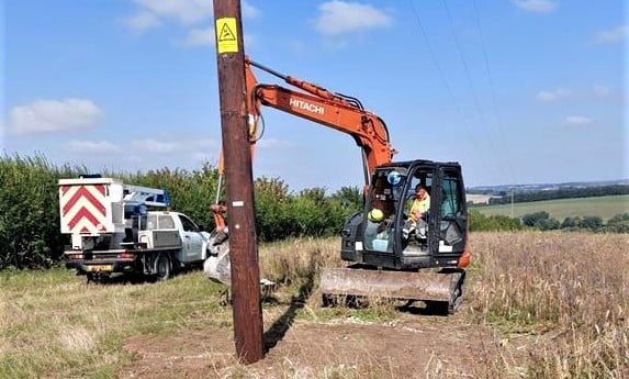 Pole being installed on meadow with grabber from vehicle