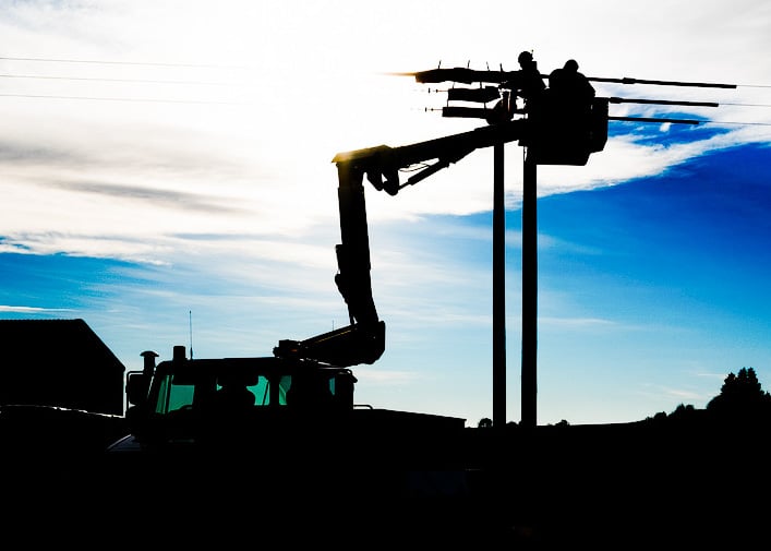 A silhouetted image of work being done on the overhead line network 