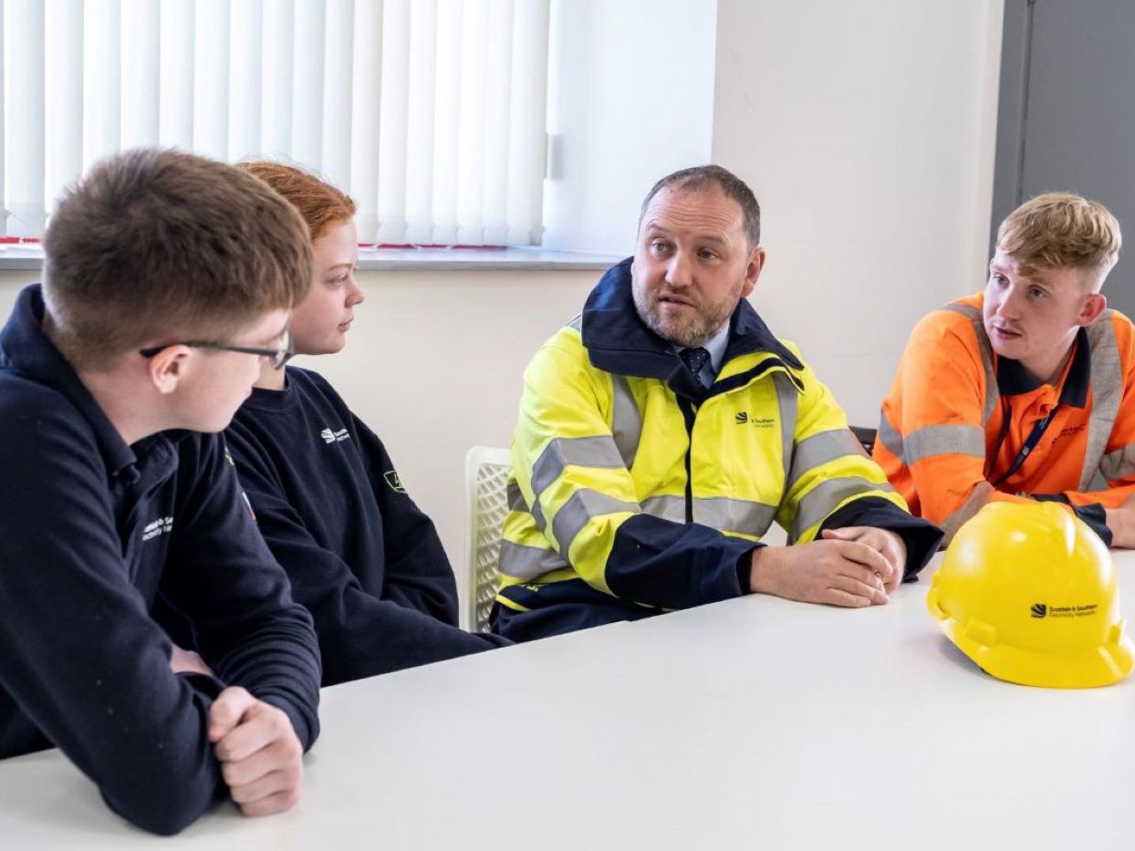 A photo of Ian Murray MP sitting down chatting with 3 year two apprentices in SSEN's training centre.