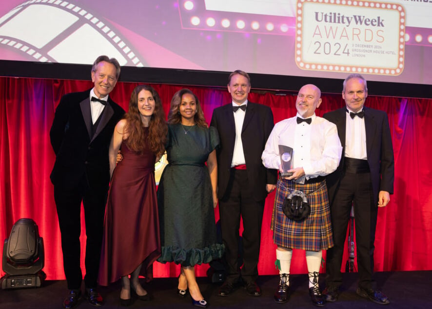 The team from SSEN who won the Utility Week Award for Unlocking Data on the stage after receiving their award from actor Richard E Grant