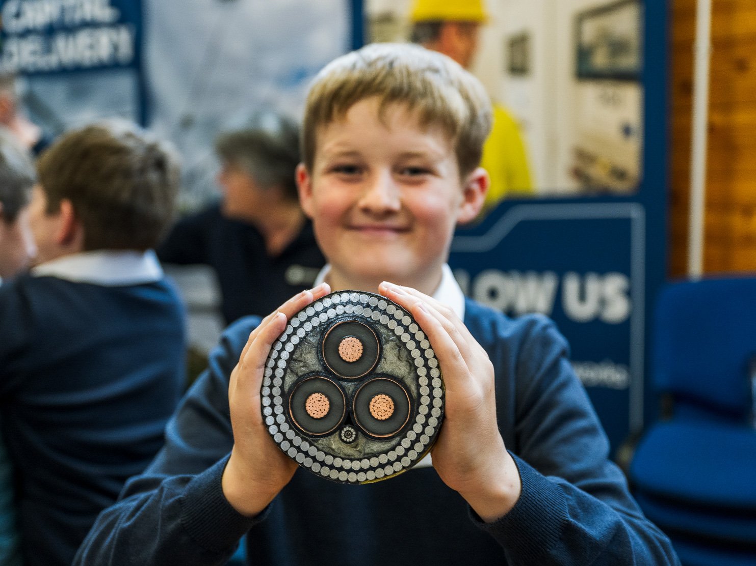 A school boy holds up a cross-section of a subsea electricity cable for the camera 