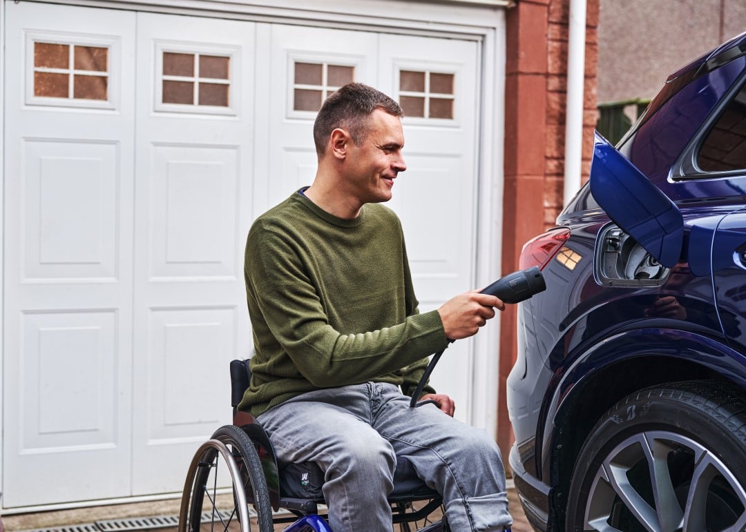 An EV driver charging their vehicle in the driveway of their home 