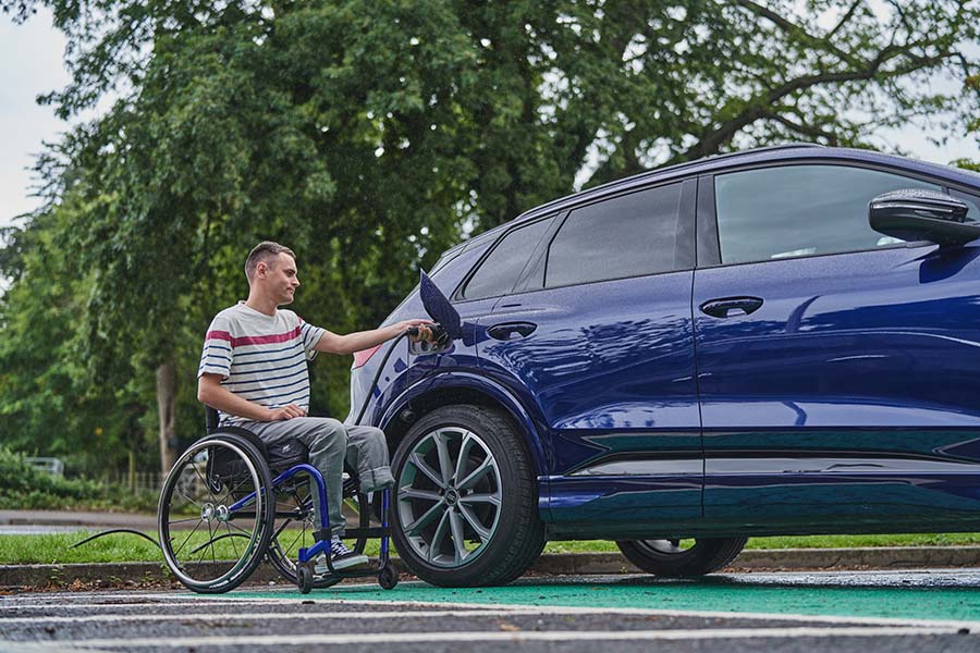 Wheelchair user plugging in electric vehicle