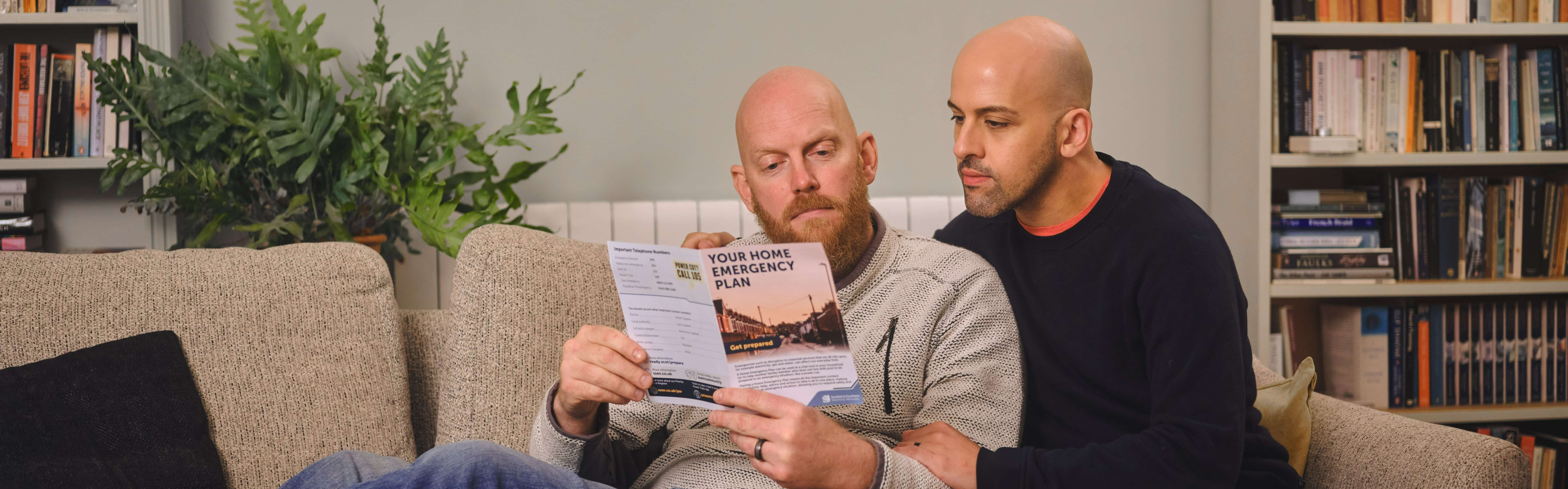 Couple on the sofa, reading SSEN leaflet.