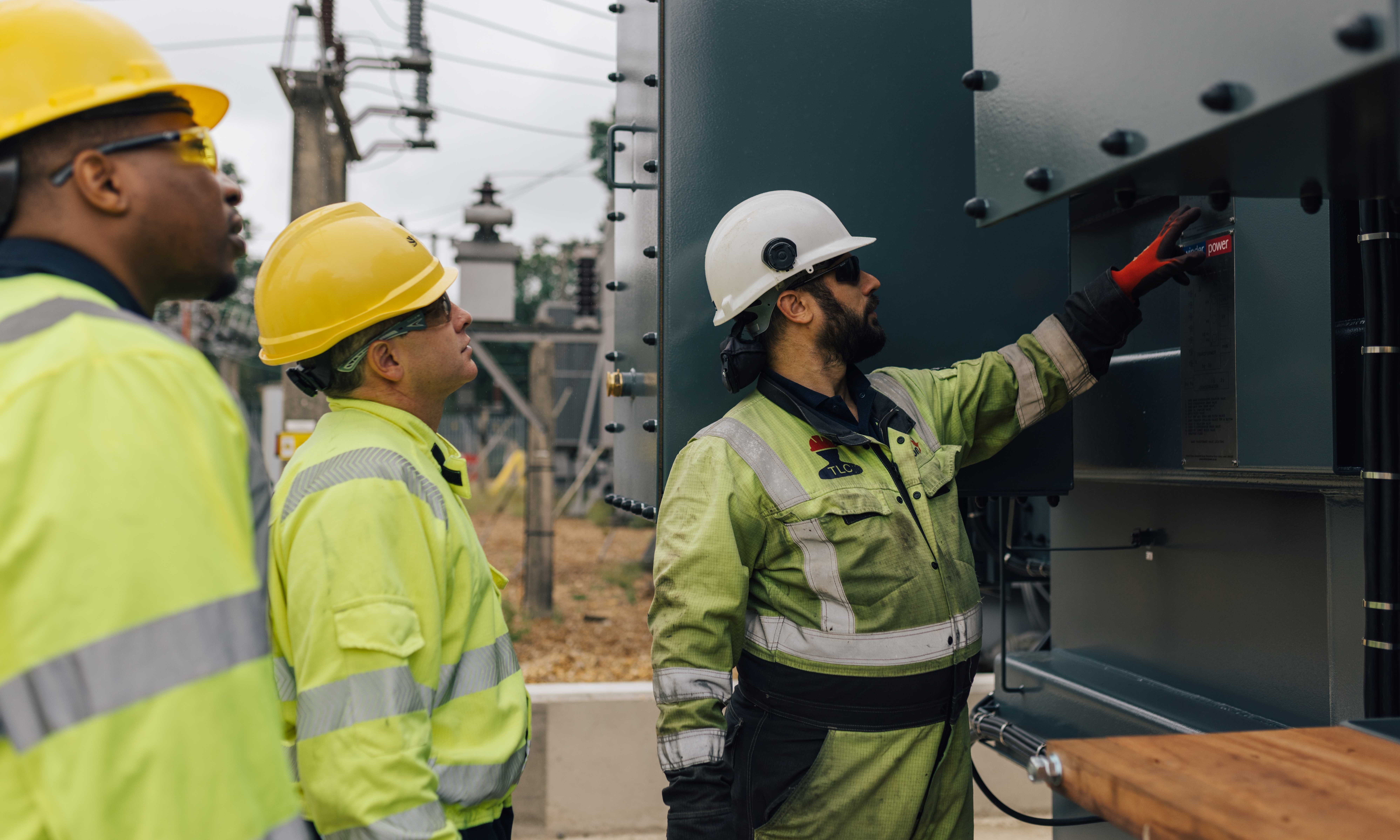 Engineers in high vis working at outdoor transformer