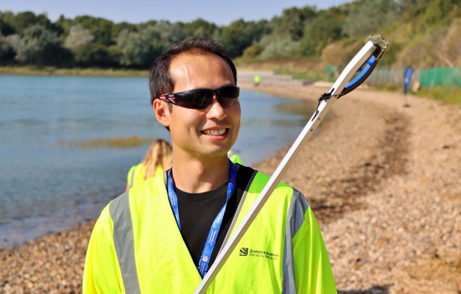 Man in high vis on beach and holding litter picking tool