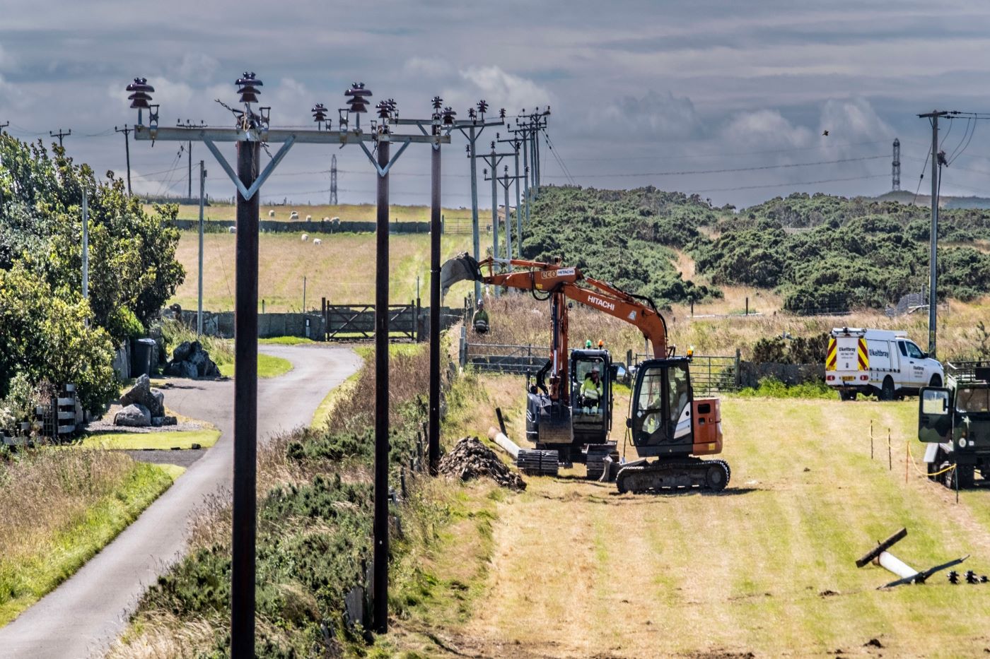Works on the replacement power line between Dounreay and Melvich; a row of poles and a digger working at a safe distance